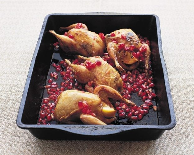 Roast marinated quails with pomegranate in a black baking tray