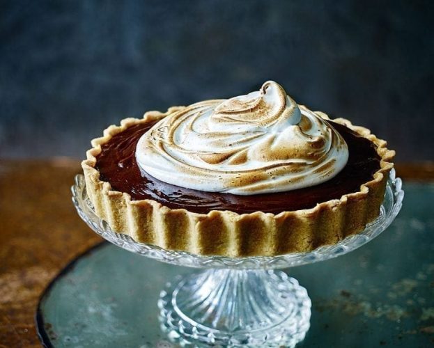 Chocolate hazelnut and cherry tart with burnt meringue shown on a pressed glass cake stand