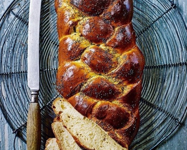 A plaited challah loaf of bread, shown with slices
