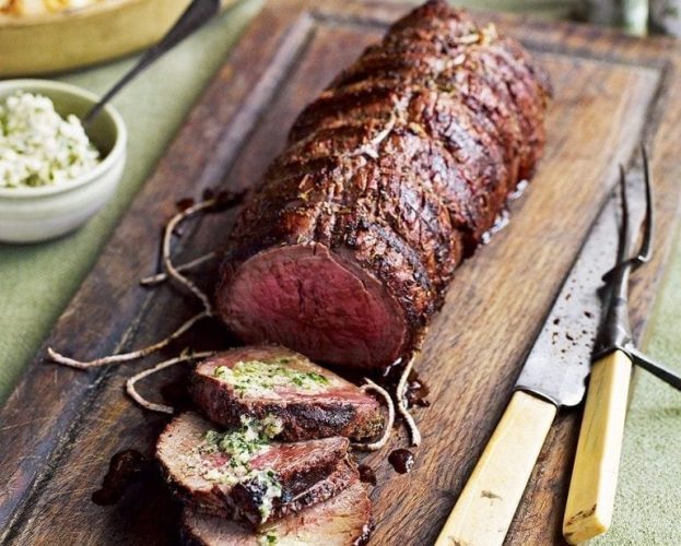 Barbecued fillet of beef, sliced, on a wooden board