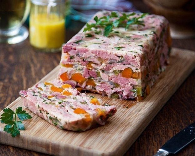 A finished ham hock terrine, shown slices and on a wooden board