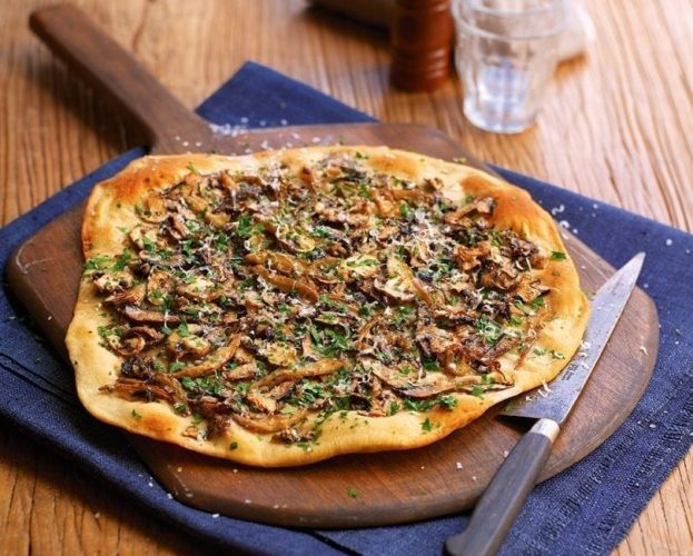 A pizza bianca (no tomato sauce) shown on a pizza paddle
