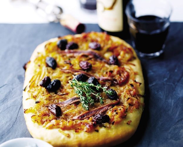A pissaladière pizza topped with black olives and caramelised onions