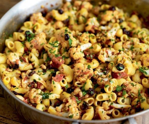 Pasta with cauliflower, currants and pine nuts in a silver pan