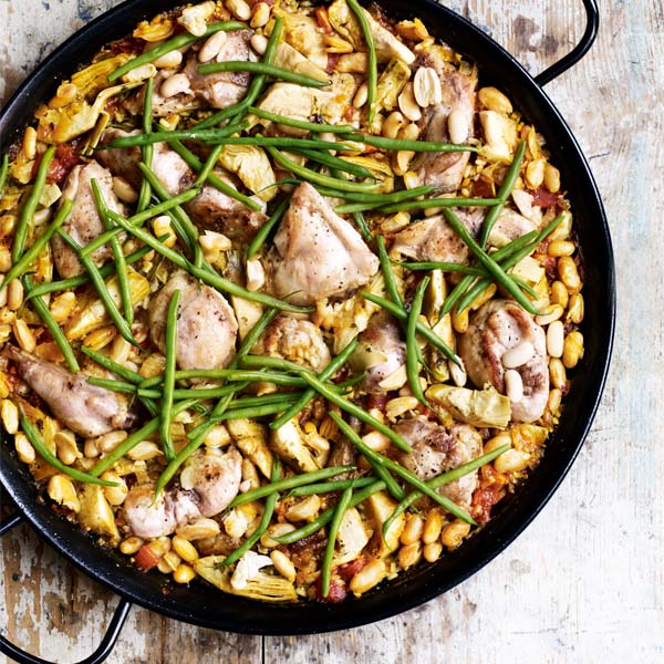 Wild rabbit paella shown in a black paella pan to illustrate a recipe