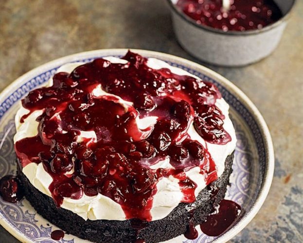 Chocolate vinegar cake with cherry compote on top - shown on a white plate