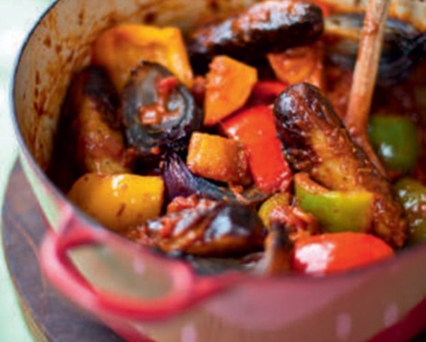 Sausage stew in a red pot, with colour red and yellow peppers