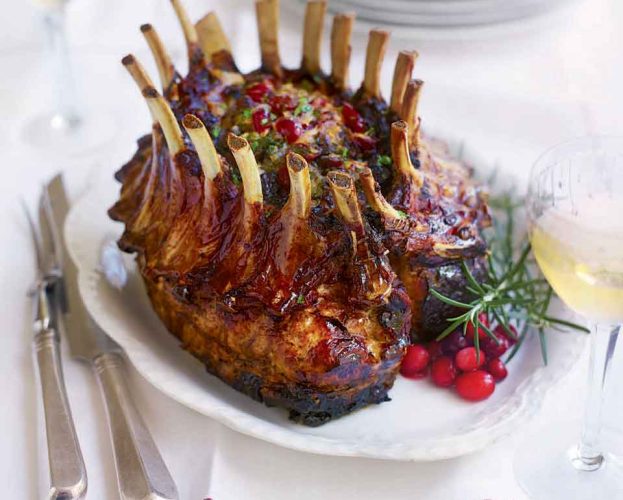 A crown roast of pork, shown roasted on a white oval plate
