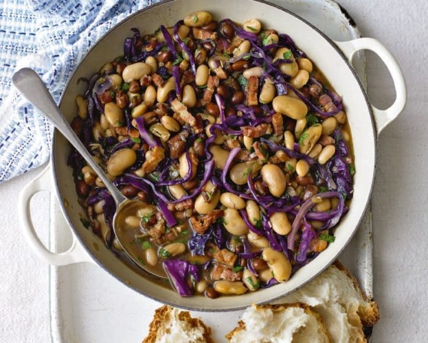 Bean and bacon stew in a white casserole dish