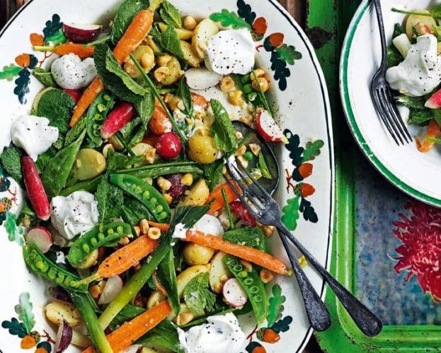 A salad of baby veg and goat's curd shown on an oval plate