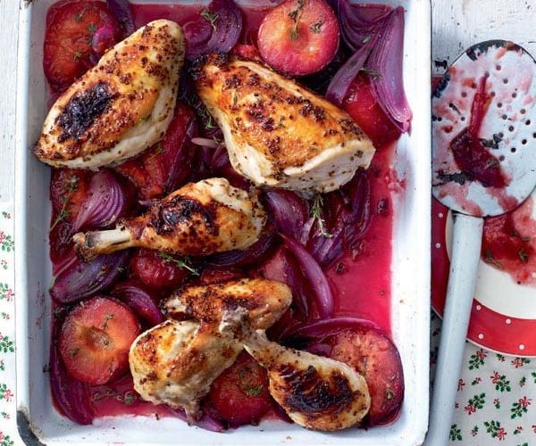 Roast chicken legs with plums in a tray