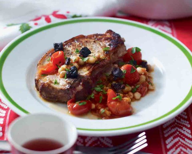 Pork chop served with beans on a white plate