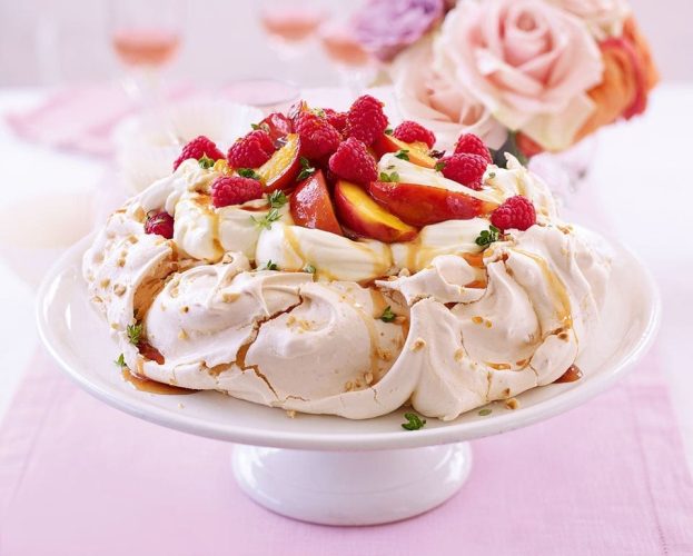 A fruit pavlova, finished, and shown off on a cake stand