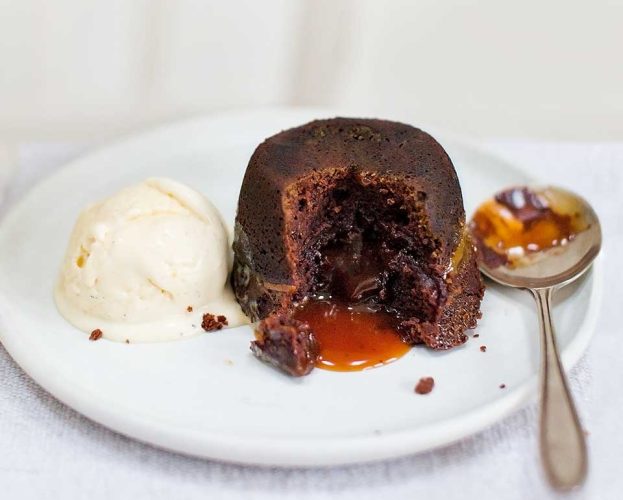 A chocolate fondant on a white plate - the inside reveals a gooey caramel centre