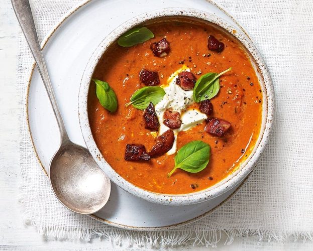 Tomato soup topped with bacon pieces, shown in a bowl with a spoon
