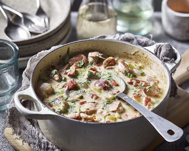 Pork cider casserole, shown in a white casserole dish with a spoon