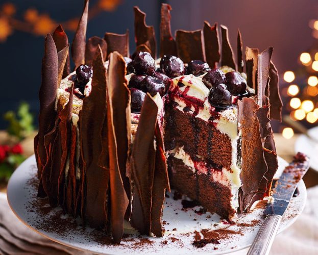 Black forest gâteau shown on a cake stand, with a slice taken out