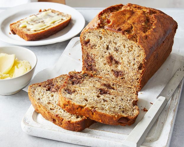 Banana bread shown sliced on a white serving plate