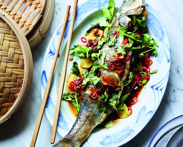 Whole steamed fish shown on a plate with chopsticks