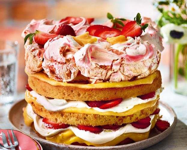 A triple-layered strawberry meringue cake on a decorated table