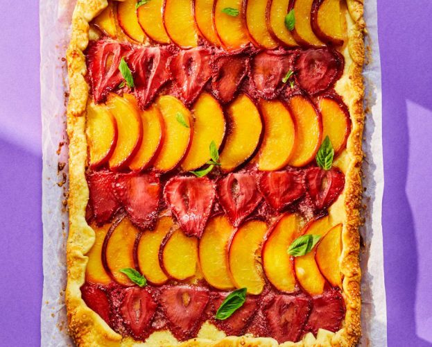 A rectangular strawberry and nectarine galette shown on a bright background