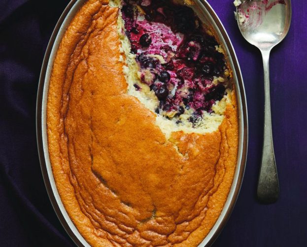 Blackcurrant clafoutis with a spoonful taken out to show the fruit inside