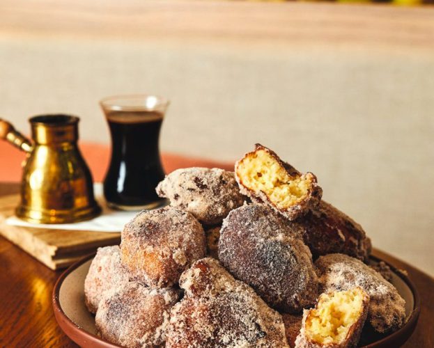 Bowl of doughnuts with coffee in background