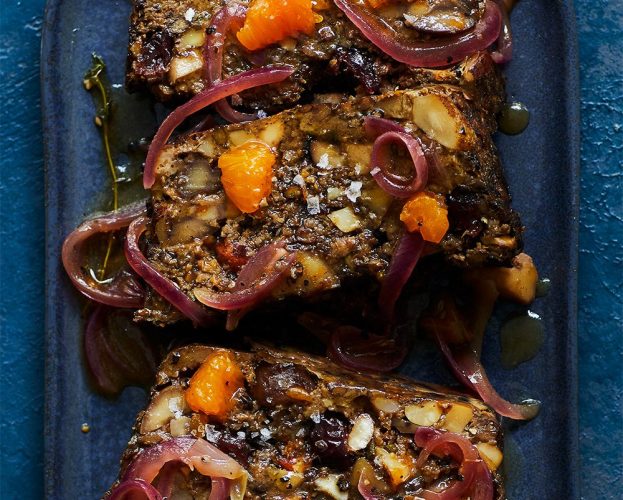 A nut roast loaf slice into three pieces and topped with clementine