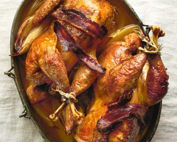 Two roasted guinea fowl with bacon in a roasting dish