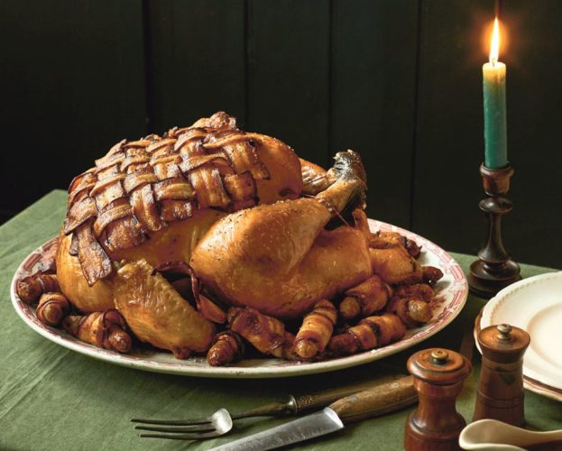 A roast turkey with a bacon lattice over the breast, displayed on a dining table