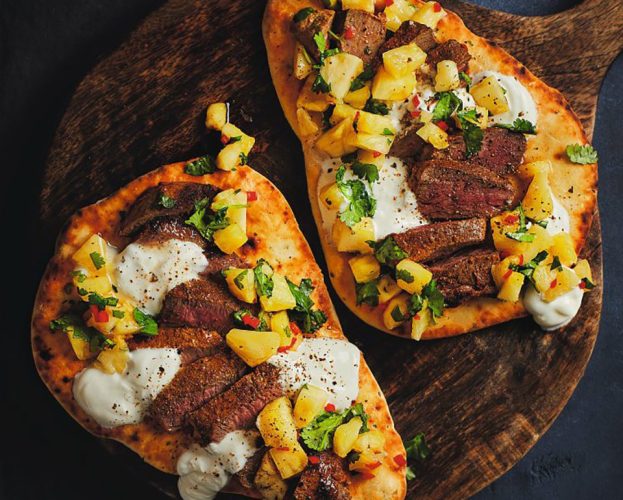 Slices of marinated vension steak on grilled naan with yogurt and pineapple salsa