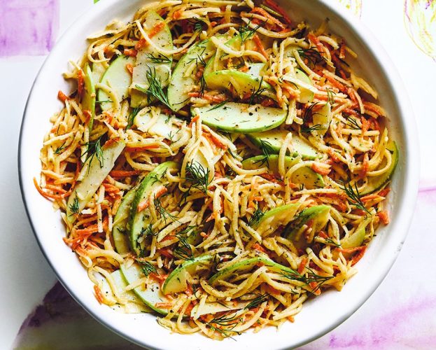 An overhead view of a vibrant bowl of swede and apple winter slaw on a colourful background