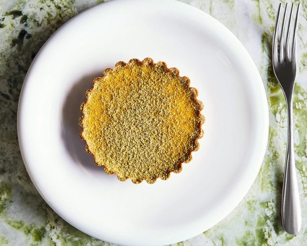 Overhead image of a custard tart dusted with green ground fennel seeds