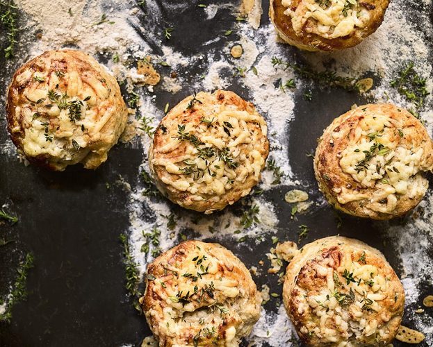 An overhead view of golden savoury scones topped with cheese and herbs