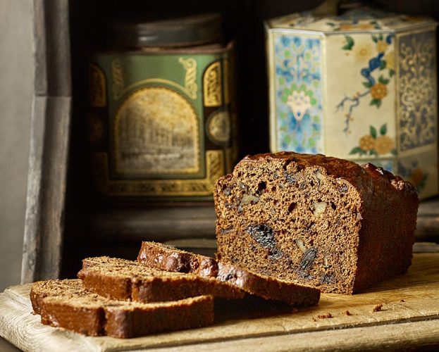 Date and walnut loaf on a wooden board, with three slices cut