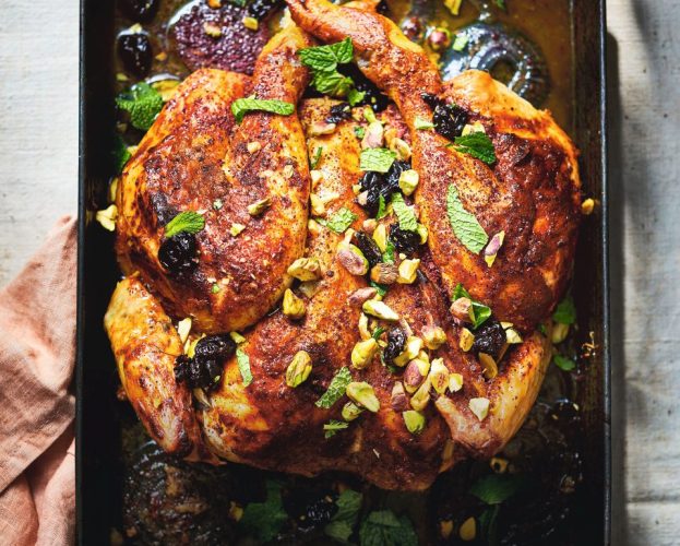 A golden spatchcocked roast chicken topped with pistachios and sour cherries
