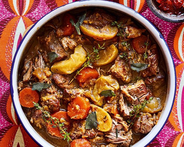 A dish of braised pork and apple with crispy sage leaves and scotch bonnet in oil on the side
