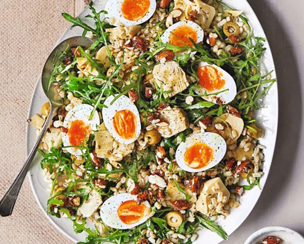 Artichoke and barley salad on a platter with soft-boiled eggs