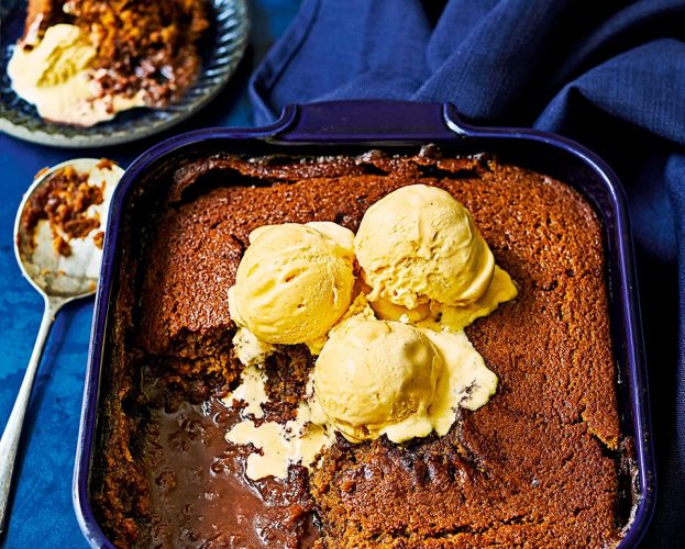 An oven dish of malt chocolate self-saucing pudding, topped with scoops of vanilla ice cream