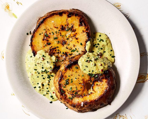 Two celeriac steaks with curried pink peppercorn sauce on a white plate