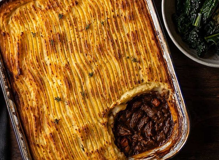 Venison cottage pie with golden celeriac mash in a large dish, one portion removed to show the rich mushroom filling